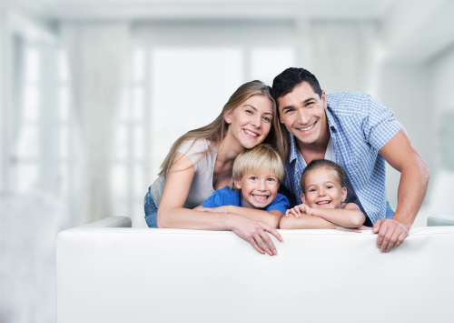 Happy family of four smiling at home, representing family-focused eye care services
