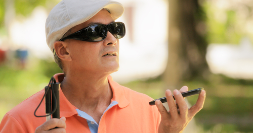 Visually impaired man using a white cane and smartphone voice assistant for navigation