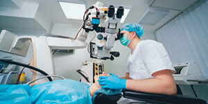 Ophthalmologist performing eye surgery using an operating microscope in a sterile clinical environment