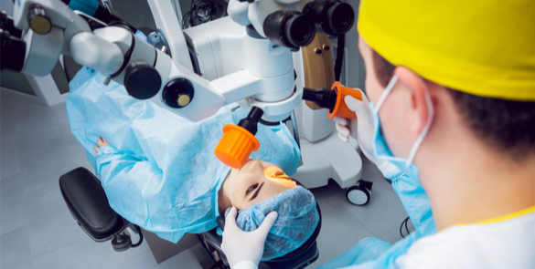 Patient receiving eye treatment under a surgical microscope in a clinical setting